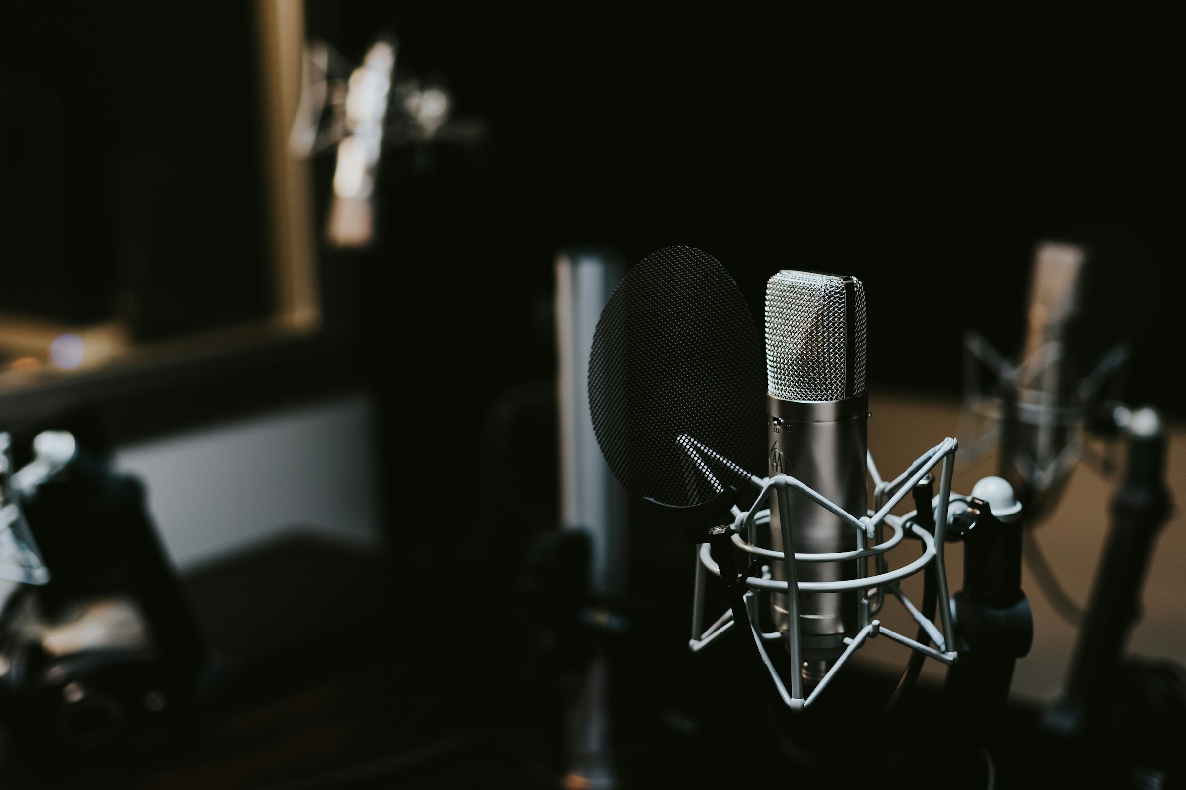 Studio condenser microphone with pop filter in a warmly lit room